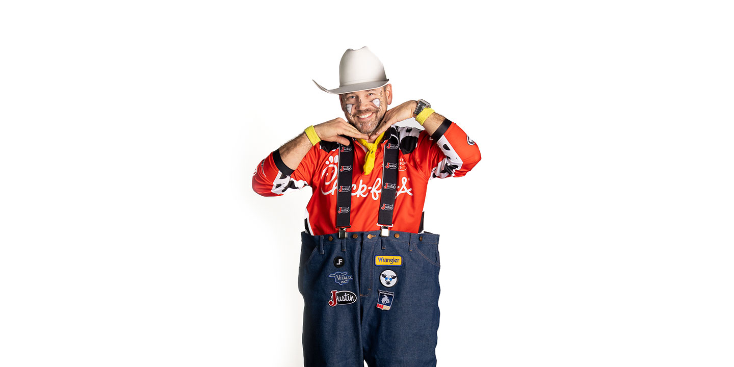El barrendero profesional Matt Merritt, vestido con una camisa roja, un sombrero de vaquero blanco y sonriendo, con las manos debajo de la barbilla, tratando de verse lindo.